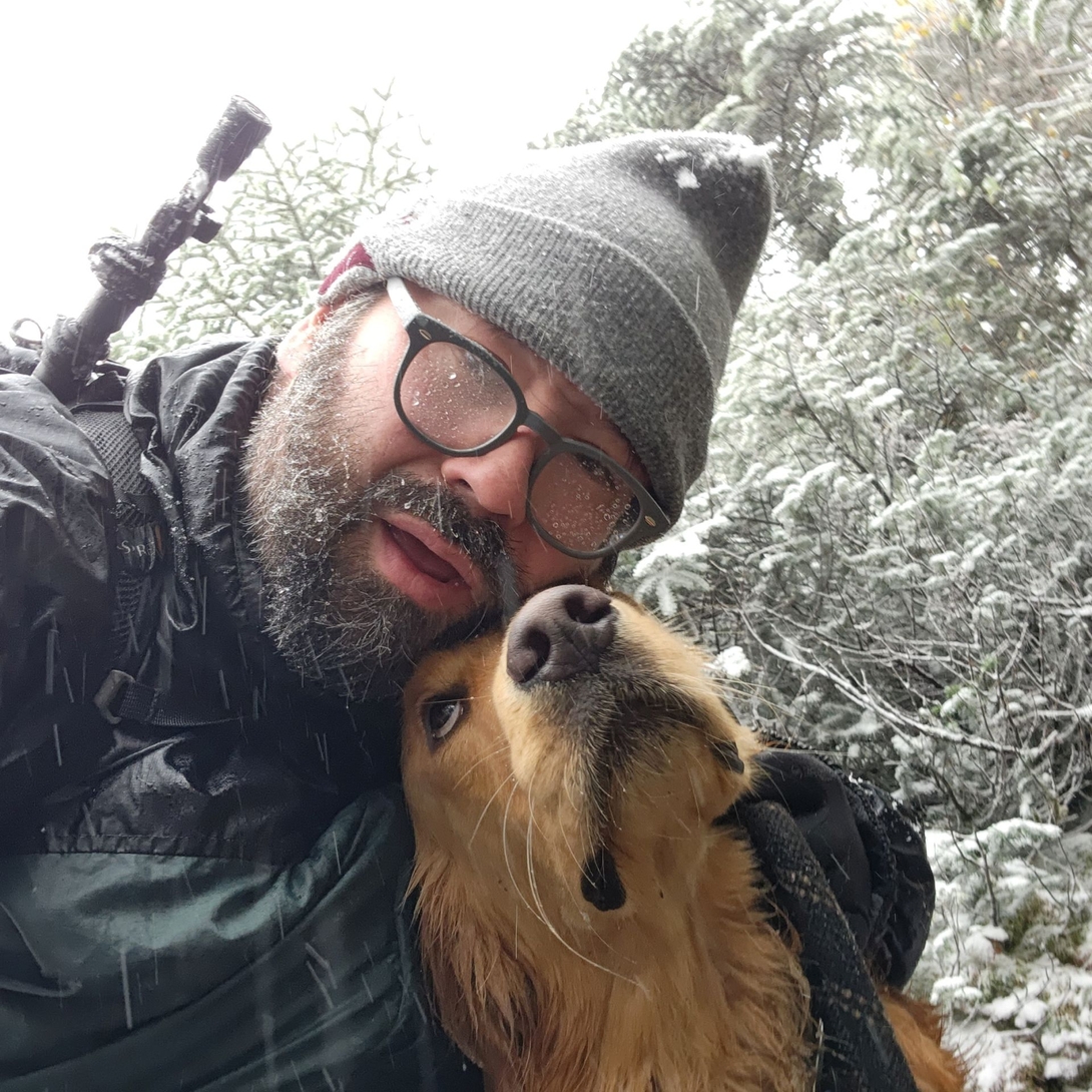 Adam and Sunny touch noses in a snowy forest on Mount Colden.