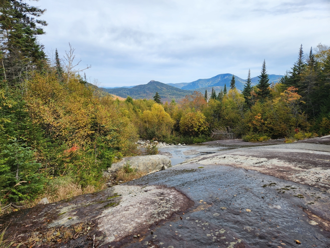 The open rock slide descends toward autumn-colored mountains below Dix.