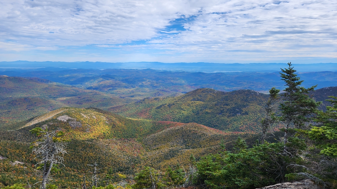 The Beck-horn and Grace Peak rise above autumn valleys, with Lake Champlain visible in the distance from Dix Mountain.