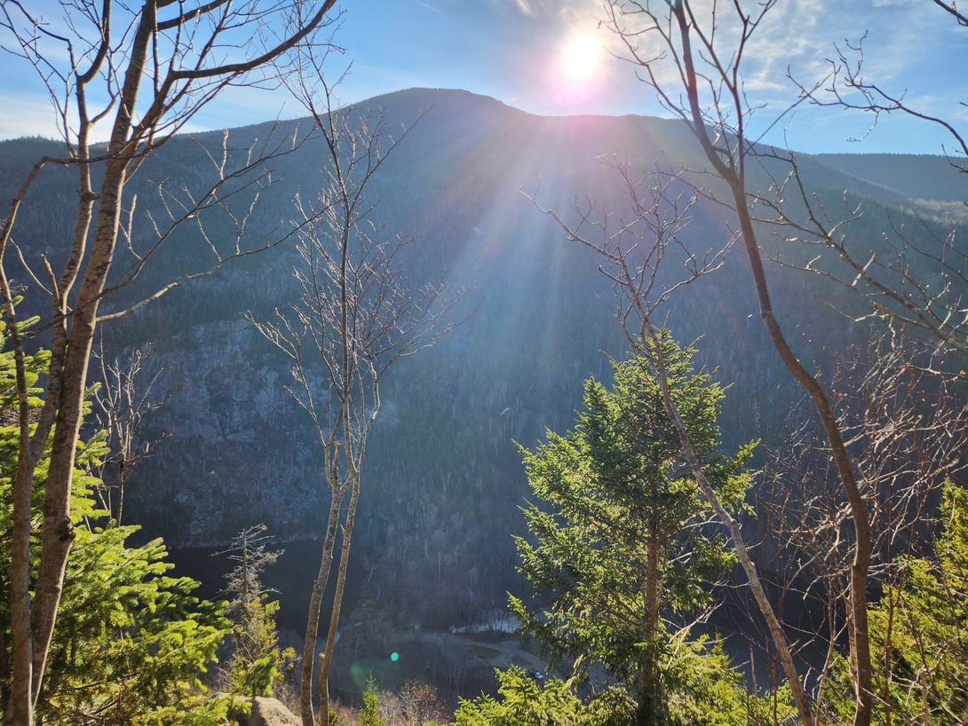 Cascade Mountain rises beyond the sunlit trees at the top of the valley ridge.
