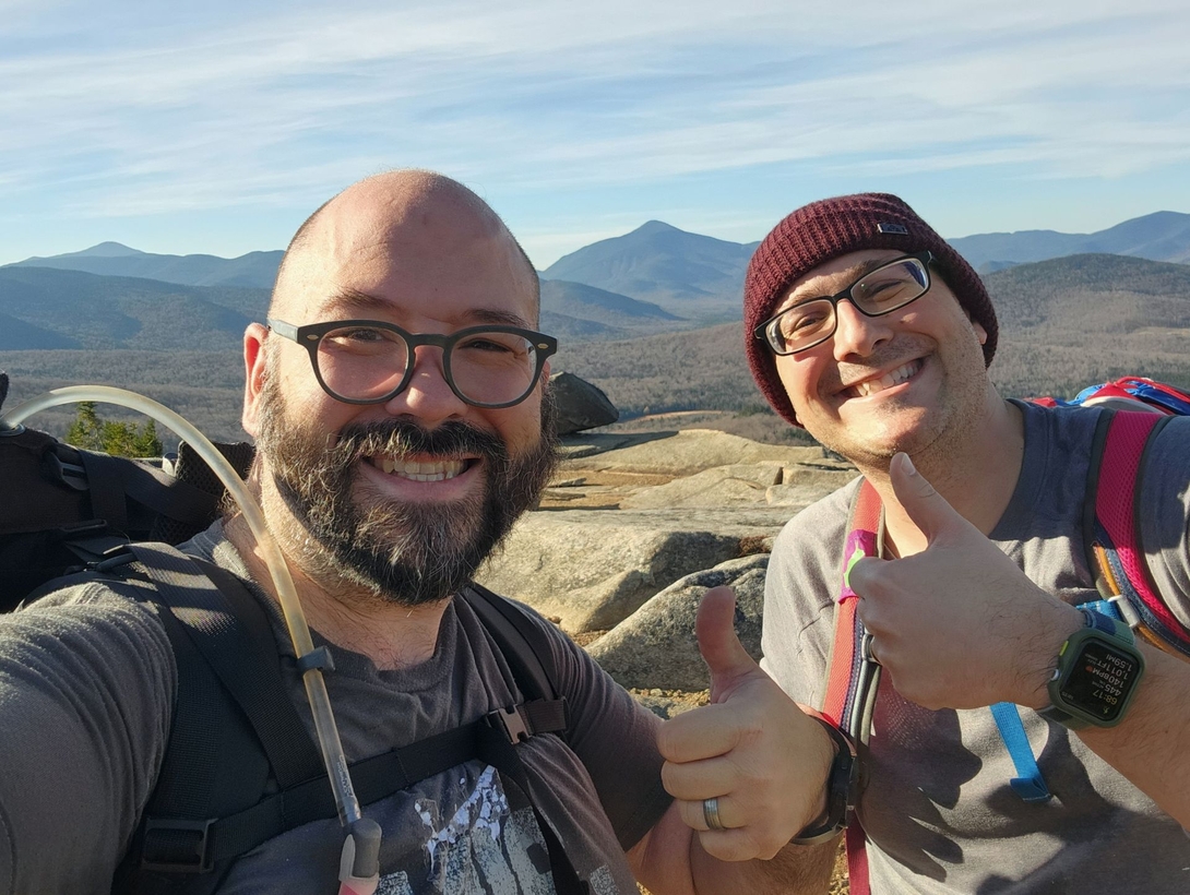 Adam and Chris smile together at Balanced Rocks during their Pitchoff Mountain hike.